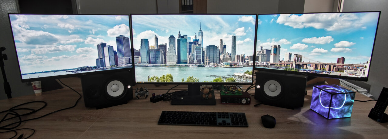 Photo of my desk. Three screens and the LED cube at one side.
