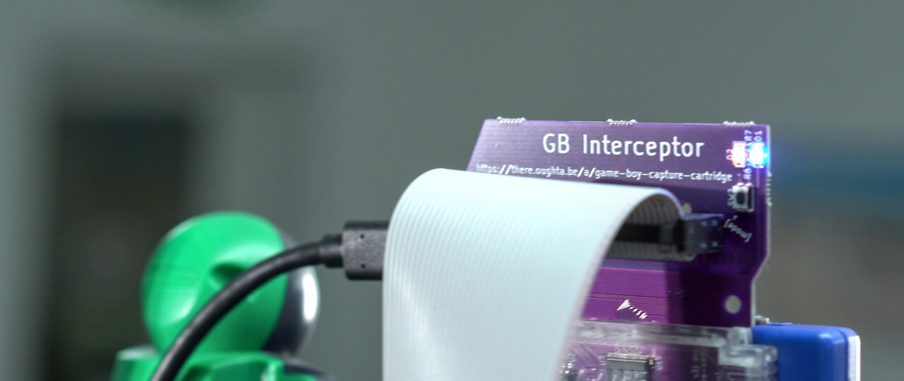 View from the back of the previous photo. Now the GB Interceptor is visible on the right with the long ribbon cable attached to it and the label GB Interceptor well visible. On the left is the Game Boy Camera (slightly blurred outside the focal plane).